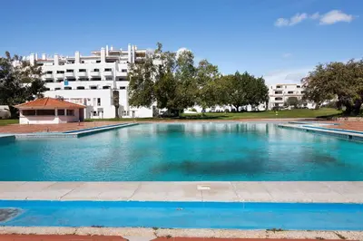 an empty swimming pool with a brick floor and a blue sky at Magnificent Beach Apartment in Albufeira