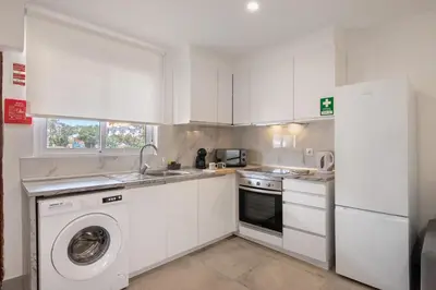 a kitchen and living room with a couch and a table at Stunning Modern Apartment In Oura in Albufeira