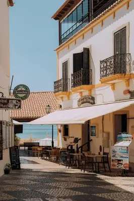 a patio with tables and umbrellas in front of a building at Garrett by MTPhomes in Albufeira