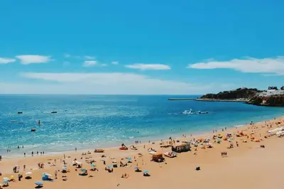 a group of people on a beach with the ocean at Garrett by MTPhomes in Albufeira