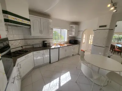 a kitchen with white cabinets and a table and chairs at Vilamoura Beach Villa with Private Pool in Quarteira