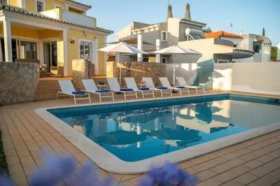 a swimming pool with chairs and a house at Vilamoura Beach Villa with Private Pool in Quarteira