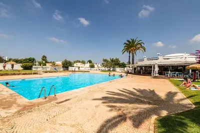 a large swimming pool with people sitting around it at Vilamoura Beach Villa by nature with Olympic Pool in Quarteira