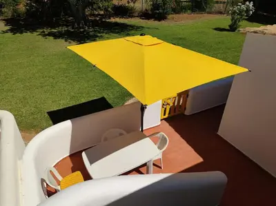 a yellow umbrella on a patio with a chair and a table at Vilamoura Beach Villa by nature with Olympic Pool in Quarteira