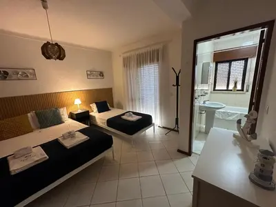 a hotel room with two beds and a bathroom at Âncora by FHR a 600m da praia in Quarteira
