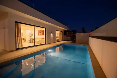 a swimming pool in front of a house at night at Sirius House in Guia