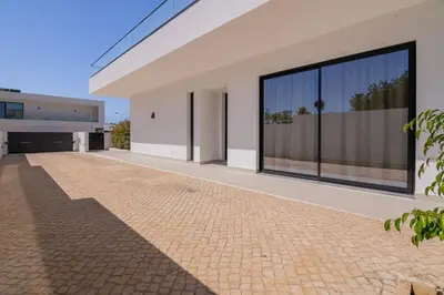 a white house with large windows and a brick driveway at Sirius House in Guia