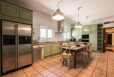 a kitchen with green cabinets and a table with chairs at Villa Monte dos Agostos by Boaz Rentals in Santa Bárbara de Nexe