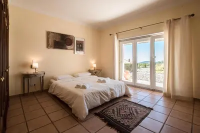 a bedroom with a large bed and a large window at Villa Monte dos Agostos by Boaz Rentals in Santa Bárbara de Nexe