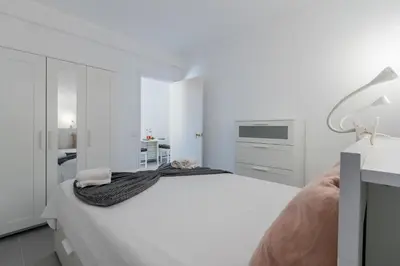 a white bedroom with a bed and a desk at Pinhal da Praia by Garvetur in Quarteira