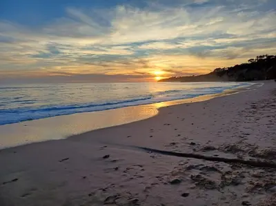 a sunset on a beach with footprints in the sand at Balaia Praia in Albufeira