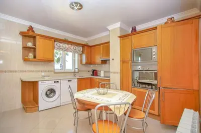 a kitchen with a table and a washing machine at Quinta do Sol in Guia