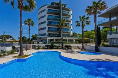 a swimming pool in front of a building at Sol e Mar in Quarteira