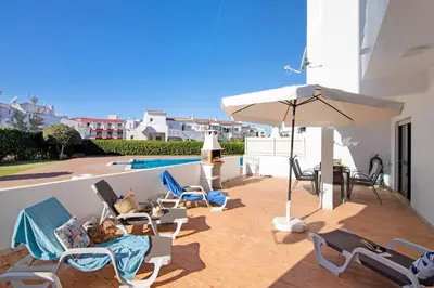 a patio with chairs and an umbrella next to a pool at Apartment Zeza in Albufeira