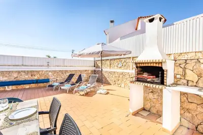 a patio with a fireplace and a table and chairs at Villa Felizalgarve in Albufeira
