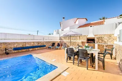 a patio with a table and chairs next to a swimming pool at Villa Felizalgarve in Albufeira