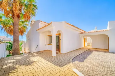 a large white house with a palm tree at Villa Garbino in Albufeira
