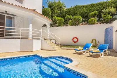 a swimming pool with two blue chairs and a house at Villa Jasmin Marina in Albufeira