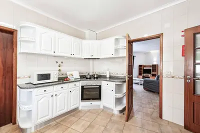 a kitchen with white cabinets and a microwave at Villa Jasmin Marina in Albufeira