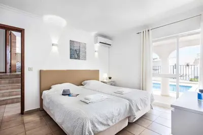 a white bedroom with a bed and a large window at Villa Jasmin Marina in Albufeira
