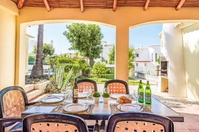 a table with chairs and wine bottles on a patio at Villa Pardal in Albufeira
