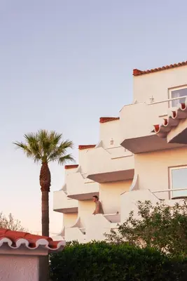 a man standing on the ledge of a building with a palm tree at Outsite Vilamoura in Quarteira