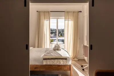 a bedroom with a bed and a large window at Outsite Vilamoura in Quarteira