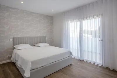 a bedroom with a white bed and a large window at Crystal bay in Albufeira