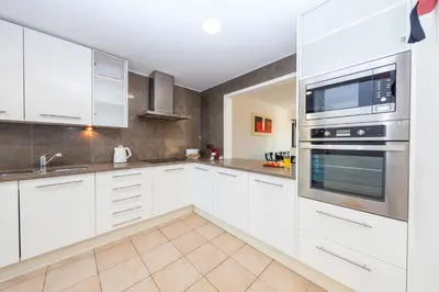 a kitchen with white cabinets and stainless steel appliances at Townhouse Ocean Joy by Algarve Vacation in Albufeira