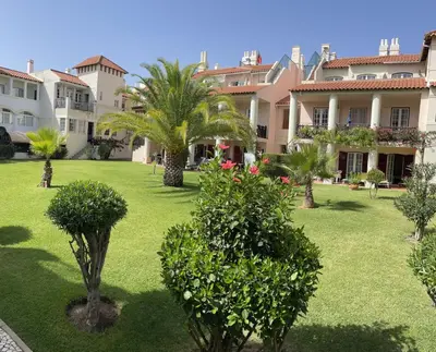 a courtyard of a building with palm trees and bushes at Old Village Vilamoura Beautiful 3 Bed townhouse in Vilamoura