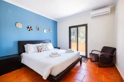 a blue bedroom with a bed and a chair at Villa Laranja in Guia