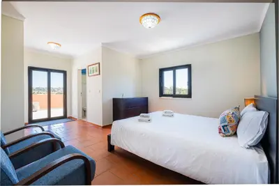 a bedroom with a large white bed and two chairs at Villa Laranja in Guia