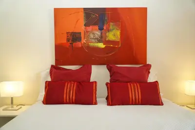 a bedroom with a bed with red pillows and a painting at Sacada Apartment in Guia