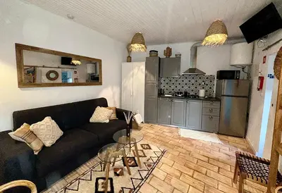 a living room with a black couch and a kitchen at Casa Da Alegria in Albufeira