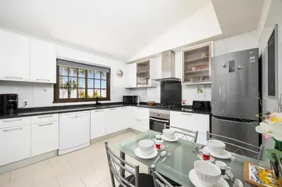 a kitchen with white cabinets and a glass table at Villa Cristina 15 in Albufeira