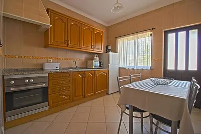 a kitchen with a table and a white refrigerator at Dinita Apartamentos in Albufeira