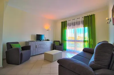 a living room with a couch and chairs and a tv at Dinita Apartamentos in Albufeira