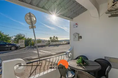 a balcony with a table and a clock on a street at #253 Fernando Pessoa 28 by Home Holidays in Albufeira