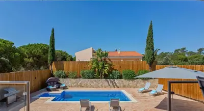 a swimming pool in a backyard with a wooden fence at Ville Verde in Loulé