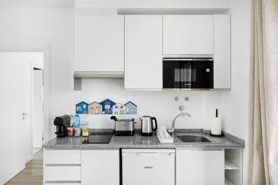a white kitchen with white cabinets and a sink at Faro Nony Apartment by Get Your Stay in Faro