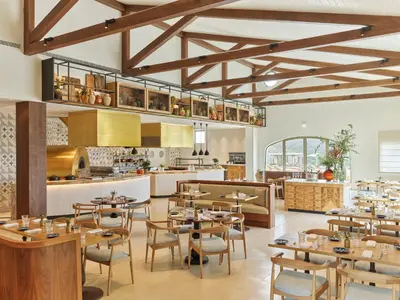 a restaurant with wooden tables and chairs and a kitchen at Viceroy Residences at Ombria Algarve in Loulé