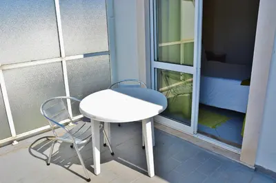 a small white table and a chair on a balcony at Residencial A Doca in Faro