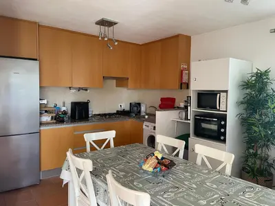 a kitchen with a table with chairs and a kitchen with a refrigerator at OuraSea Apartment in Albufeira