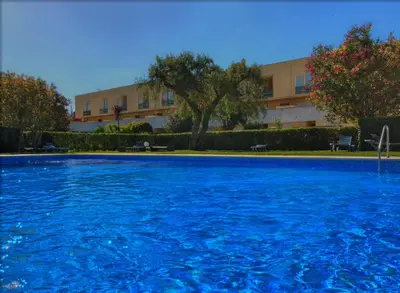 a large pool with blue water in front of a building at Barca do Lago - Vilamoura in Vilamoura