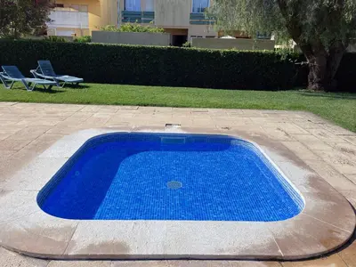 a blue swimming pool in a yard with two chairs at Barca do Lago - Vilamoura in Vilamoura