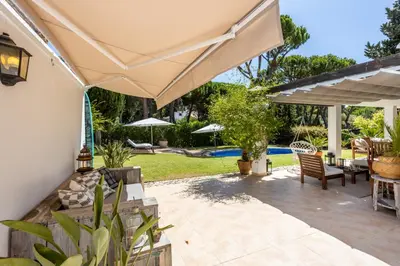 a patio with a table and chairs under aige umbrella at Villa Bonita in Albufeira