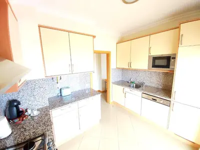 a kitchen with white cabinets and granite counter tops at Sea View Penthouse in Albufeira in Albufeira