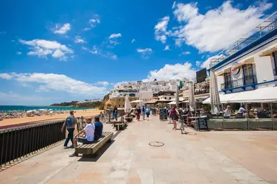 a group of people sitting on a bench near the beach at Sea View Penthouse in Albufeira in Albufeira