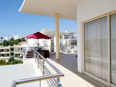 a balcony with a red umbrella on a building at Sea View Penthouse in Albufeira in Albufeira