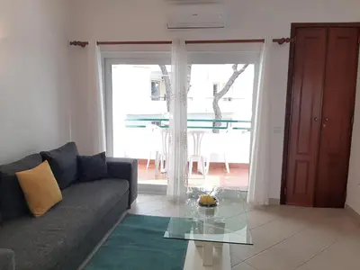 a table with wine glasses and a couch on a balcony at Beach Falésia in Albufeira